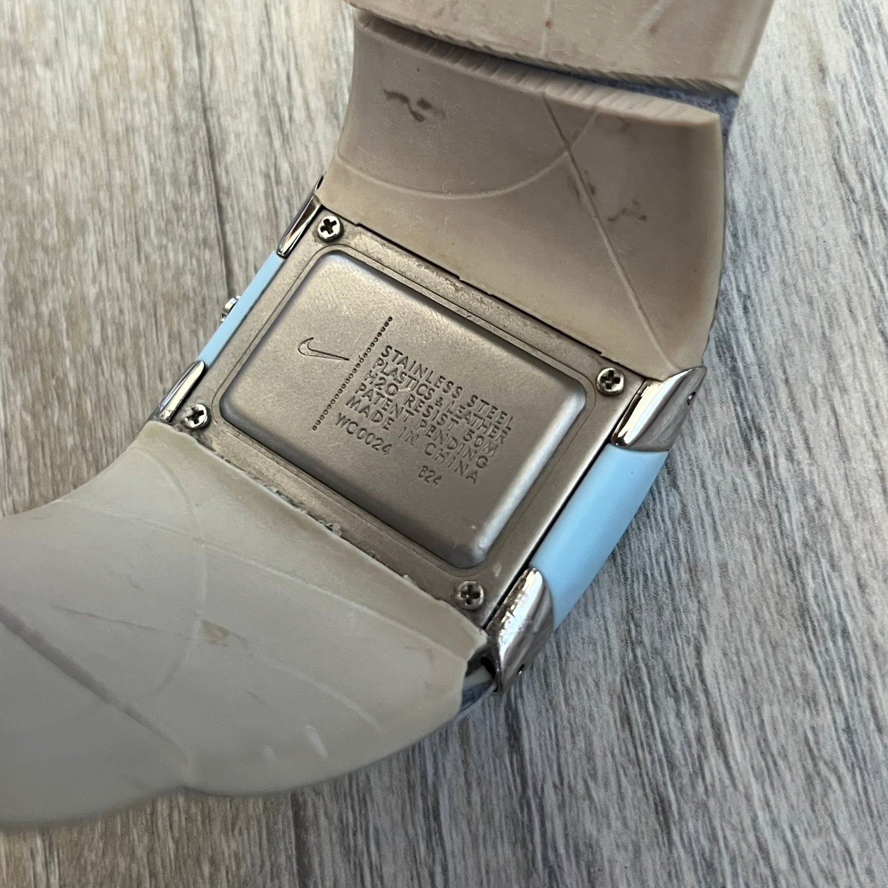 Nike WC0024-624 Merge Attract Baby Blue Digital Watch is a digital wristwatch featuring a silver-tone stainless steel case with a analog display. The straps are baby blue with engraved floral pattern graphics on the outer side and a beige inner lining, made from a combination of leather, plastic, and rubber materials. The dial is metallic baby blue with small dots pattern.