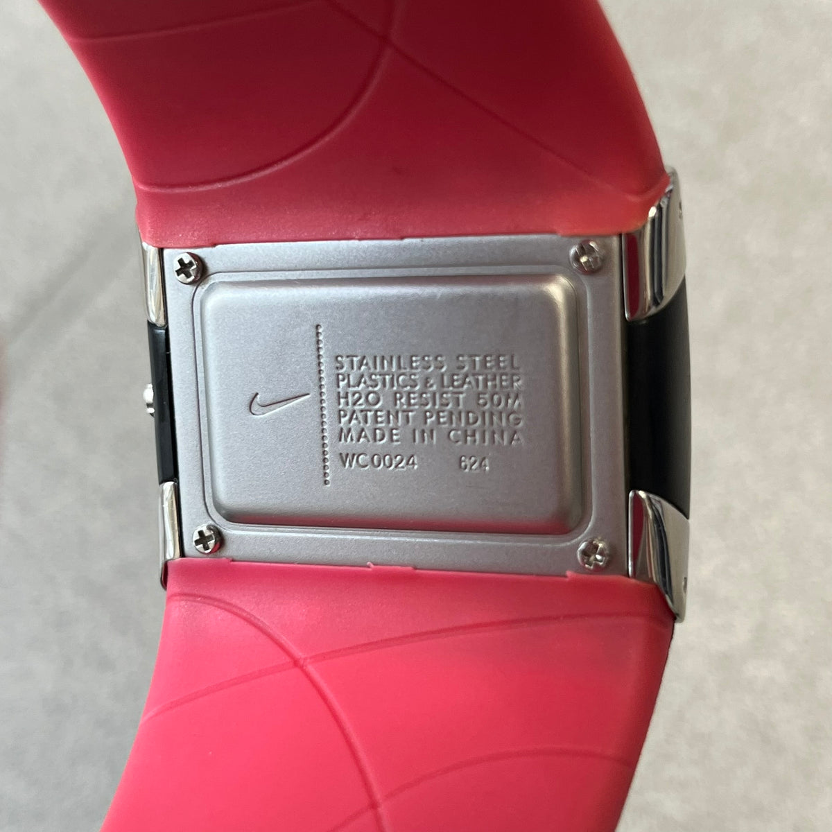 Nike WC0024-624 Merge Attract Black &amp; Pink Analog Watch is a analog wristwatch featuring a silver-tone stainless steel case. The straps are black with engraved floral pattern graphics on the outer side and a pink inner lining, made from a combination of leather, plastic, and rubber materials. The dial is metallic black with small dots pattern and pink 12 - 6 numbers.