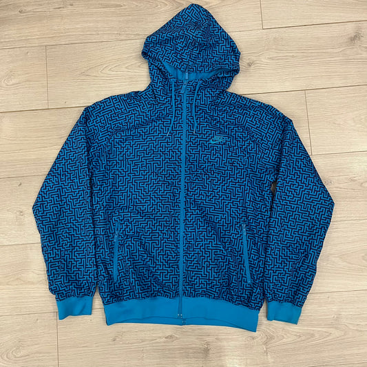 The Nike x Wood Wood “Labyrinth” Split Windbreaker (237110-400) features a full laser blue polyester body with an all-over navy labyrinth print. Designed in Copenhagen, the jacket includes zippers on the front and back allowing it to merge with other compatible models, an embroidered Nike logo and a subtle Wood Wood tag. Inside, a unique printed message from the Wood Wood founders references the jacket’s “Labyrinth” inspiration.