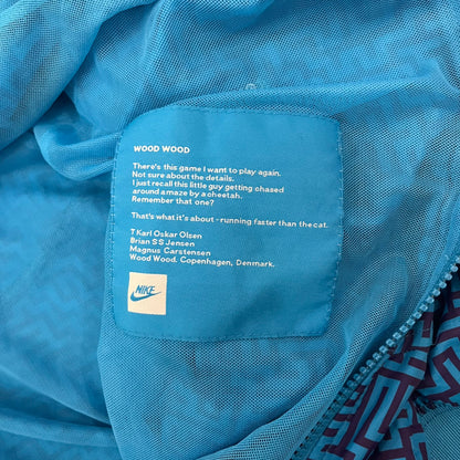The Nike x Wood Wood “Labyrinth” Split Windbreaker (237110-400) features a full laser blue polyester body with an all-over navy labyrinth print. Designed in Copenhagen, the jacket includes zippers on the front and back allowing it to merge with other compatible models, an embroidered Nike logo and a subtle Wood Wood tag. Inside, a unique printed message from the Wood Wood founders references the jacket’s “Labyrinth” inspiration.