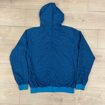 The Nike x Wood Wood “Labyrinth” Split Windbreaker (237110-400) features a full laser blue polyester body with an all-over navy labyrinth print. Designed in Copenhagen, the jacket includes zippers on the front and back allowing it to merge with other compatible models, an embroidered Nike logo and a subtle Wood Wood tag. Inside, a unique printed message from the Wood Wood founders references the jacket’s “Labyrinth” inspiration.