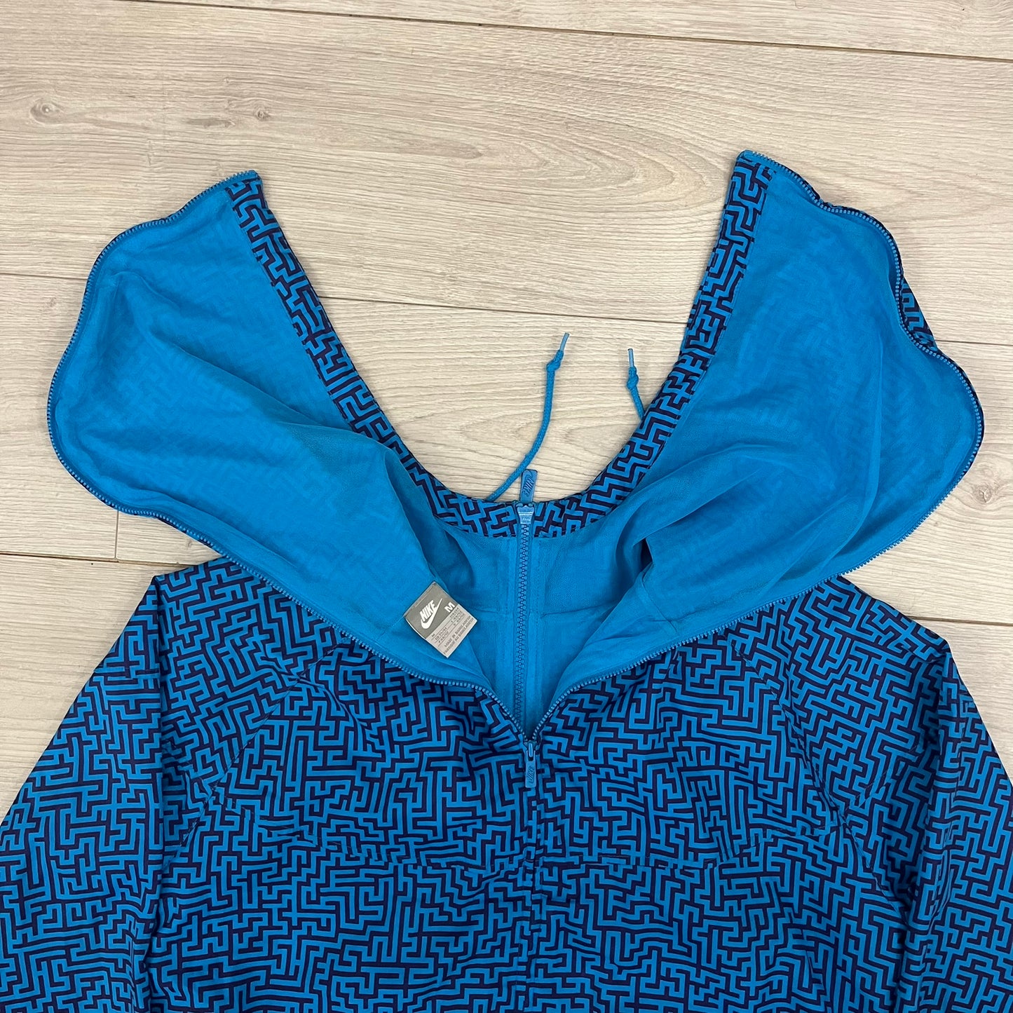 The Nike x Wood Wood “Labyrinth” Split Windbreaker (237110-400) features a full laser blue polyester body with an all-over navy labyrinth print. Designed in Copenhagen, the jacket includes zippers on the front and back allowing it to merge with other compatible models, an embroidered Nike logo and a subtle Wood Wood tag. Inside, a unique printed message from the Wood Wood founders references the jacket’s “Labyrinth” inspiration.