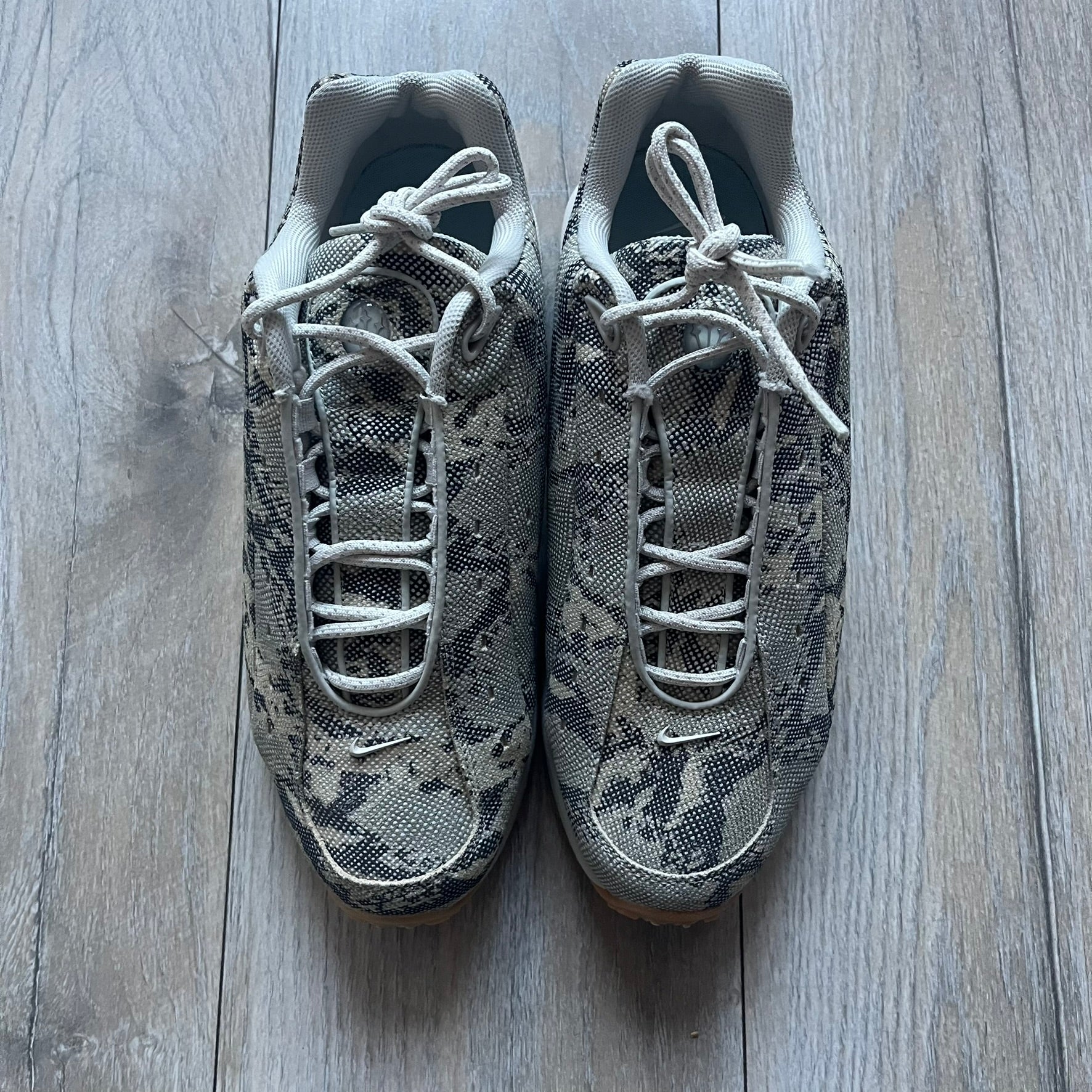 The Nike x NOCTA Hot Step Air Terra “Snakeskin” Light Bone Sneakers feature a low-top silhouette with a textured faux snakeskin upper in Light Bone tones mixed with cobblestone and gum light brown accents. The shoe includes small Swoosh logos on the sides, NOCTA three-star branding on the tongue, perforated quarter panels, and a metallic heel tag with Gore-Tex embossing. Finished with a white midsole housing a visible Air unit at the heel and a gum rubber outsole, style code DR0508-001, colorway Light Bone/