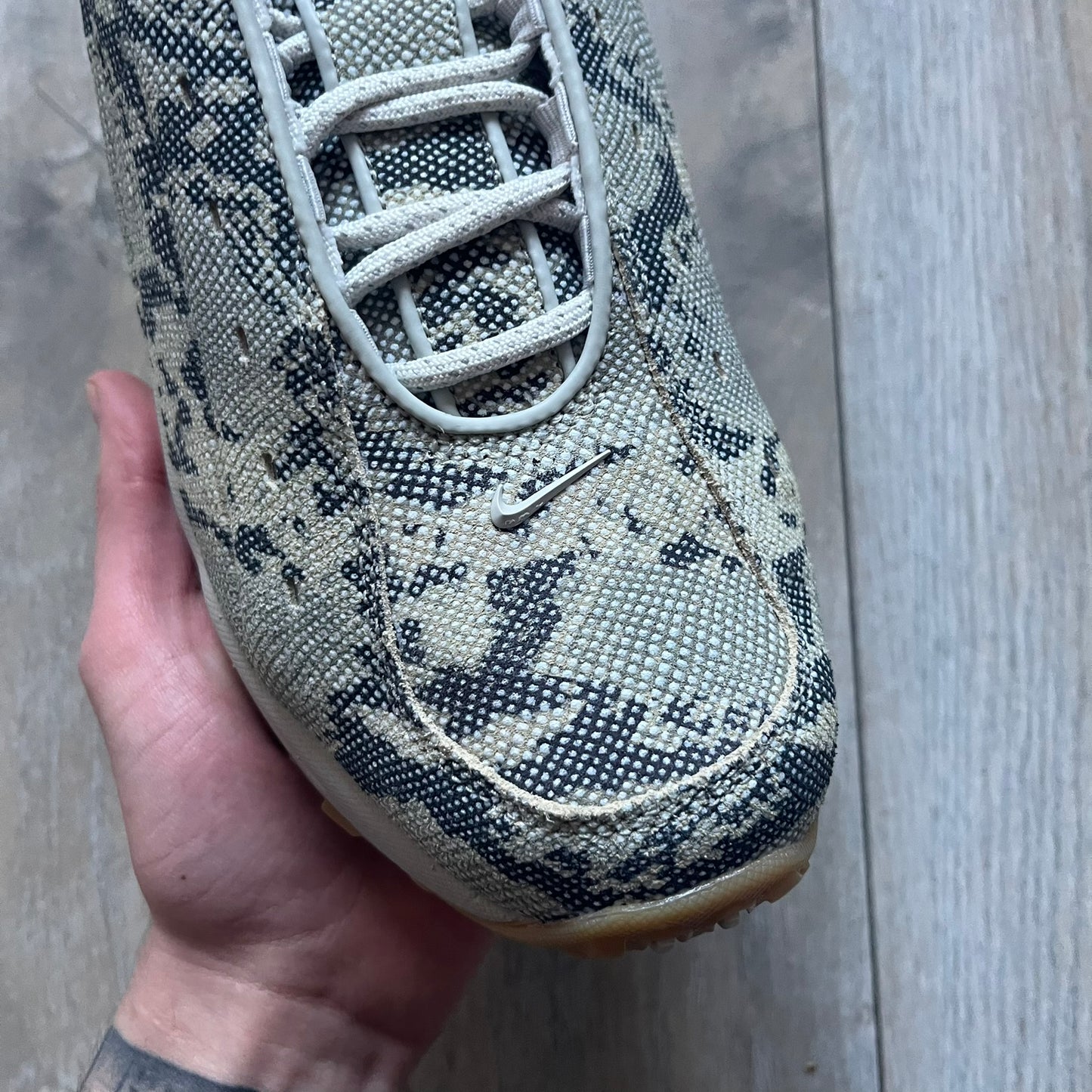 The Nike x NOCTA Hot Step Air Terra “Snakeskin” Light Bone Sneakers feature a low-top silhouette with a textured faux snakeskin upper in Light Bone tones mixed with cobblestone and gum light brown accents. The shoe includes small Swoosh logos on the sides, NOCTA three-star branding on the tongue, perforated quarter panels, and a metallic heel tag with Gore-Tex embossing. Finished with a white midsole housing a visible Air unit at the heel and a gum rubber outsole, style code DR0508-001, colorway Light Bone/