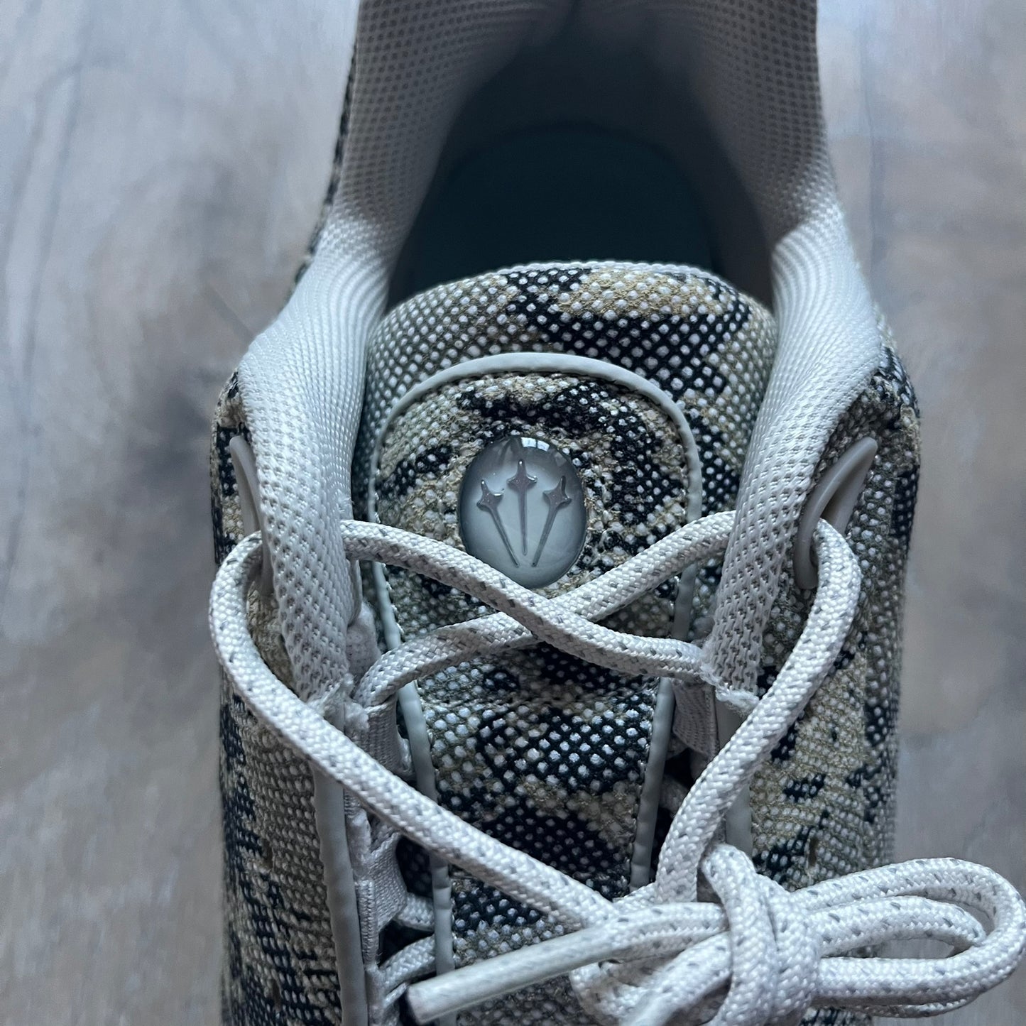 The Nike x NOCTA Hot Step Air Terra “Snakeskin” Light Bone Sneakers feature a low-top silhouette with a textured faux snakeskin upper in Light Bone tones mixed with cobblestone and gum light brown accents. The shoe includes small Swoosh logos on the sides, NOCTA three-star branding on the tongue, perforated quarter panels, and a metallic heel tag with Gore-Tex embossing. Finished with a white midsole housing a visible Air unit at the heel and a gum rubber outsole, style code DR0508-001, colorway Light Bone/