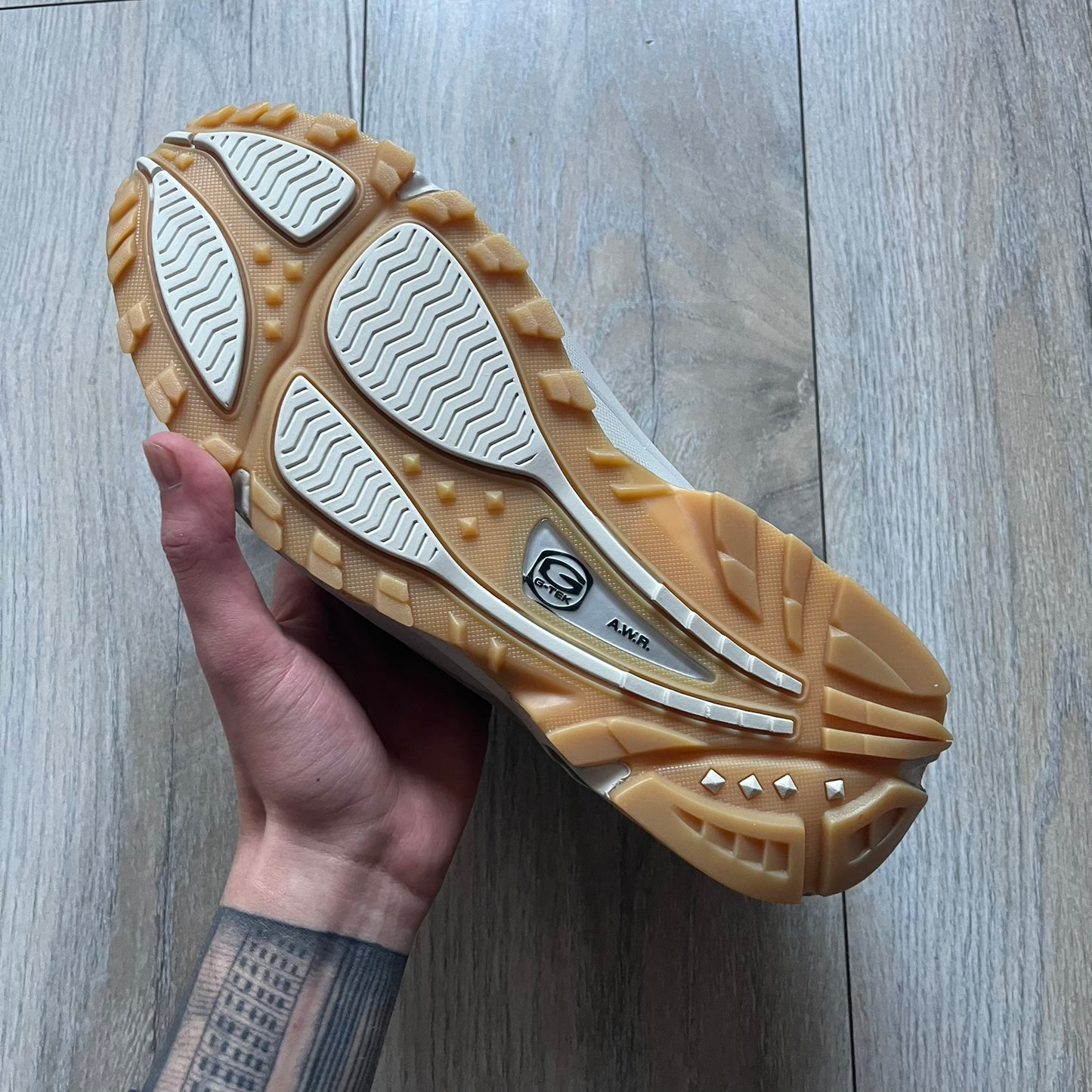 The Nike x NOCTA Hot Step Air Terra “Snakeskin” Light Bone Sneakers feature a low-top silhouette with a textured faux snakeskin upper in Light Bone tones mixed with cobblestone and gum light brown accents. The shoe includes small Swoosh logos on the sides, NOCTA three-star branding on the tongue, perforated quarter panels, and a metallic heel tag with Gore-Tex embossing. Finished with a white midsole housing a visible Air unit at the heel and a gum rubber outsole, style code DR0508-001, colorway Light Bone/