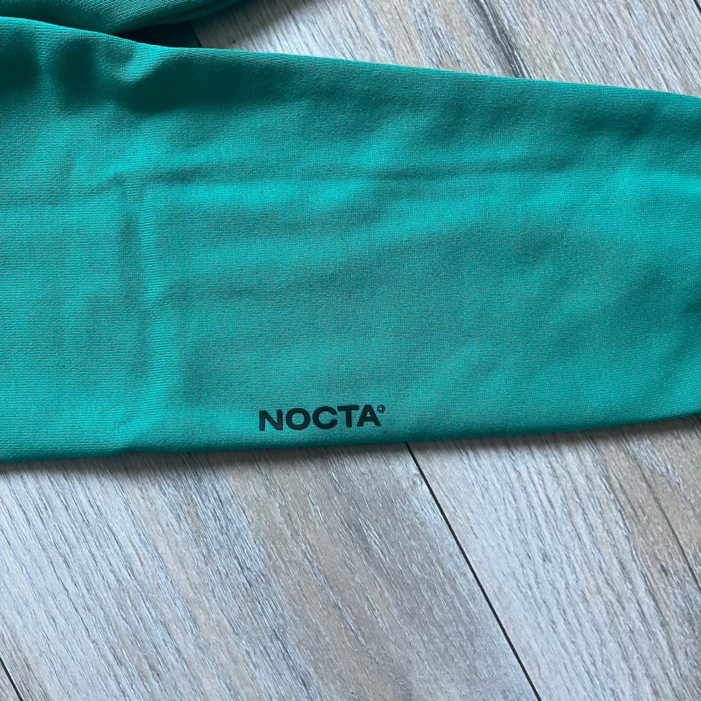 Nike x NOCTA Fleece “Neptune Green” Crewneck Sweatshirt FN8160-370 is a men’s pullover from the Cardinal Stock collection, finished in a Neptune Green/Black colorway. It features a regular fit with a round neckline, long sleeves, elastic cuffs, and an elasticated lower hem.&nbsp;Made from 82% cotton and 18% polyester fleece, the sweatshirt includes a silicone Swoosh logo and signature NOCTA branding, along with a back print, sleeve print, and 3D logo detailing. Made in Vietnam.
