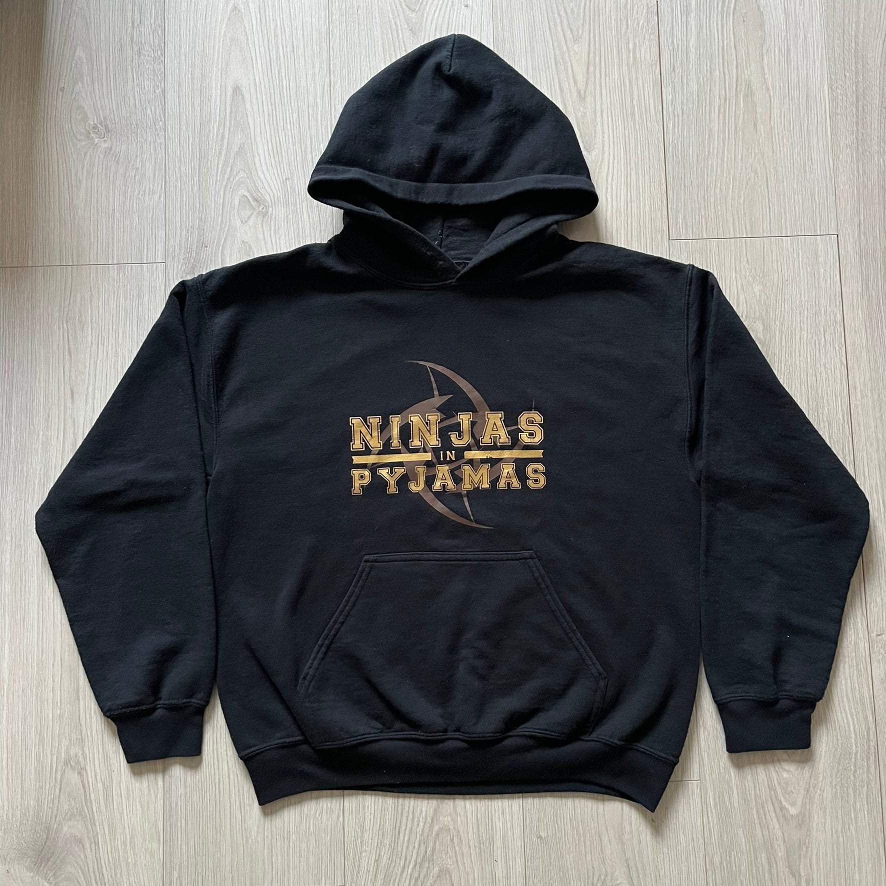 Ninjas In Pyjamas 2010’s Black Hoodie featuring the classic brown NIP logo with gold “Ninjas in Pyjamas” text across the front. Made on a Gildan Heavy Blend blank with a front pocket and adjustable hood. A vintage piece representing one of CS:GO’s most iconic teams.