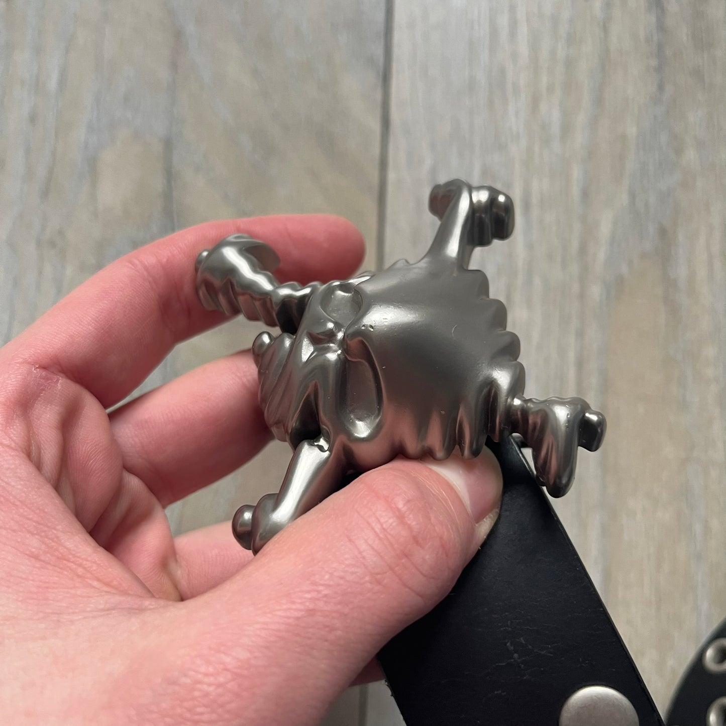 Oakley 2004 Black Leather Skull Belt is a genuine black leather belt featuring full-length holes for adjustable sizing. The belt end is embossed with a carved Oakley logo, and it includes a metal skull buckle with Oakley branding. Made in 2004, it combines durable leather construction with signature Oakley design details.