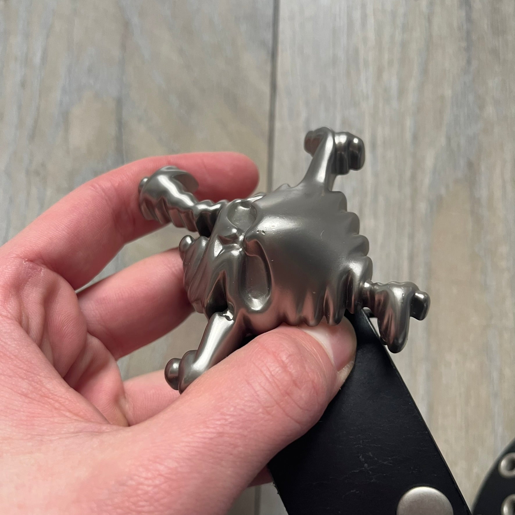 Oakley 2004 Black Leather Skull Belt is a genuine black leather belt featuring full-length holes for adjustable sizing. The belt end is embossed with a carved Oakley logo, and it includes a metal skull buckle with Oakley branding. Made in 2004, it combines durable leather construction with signature Oakley design details.