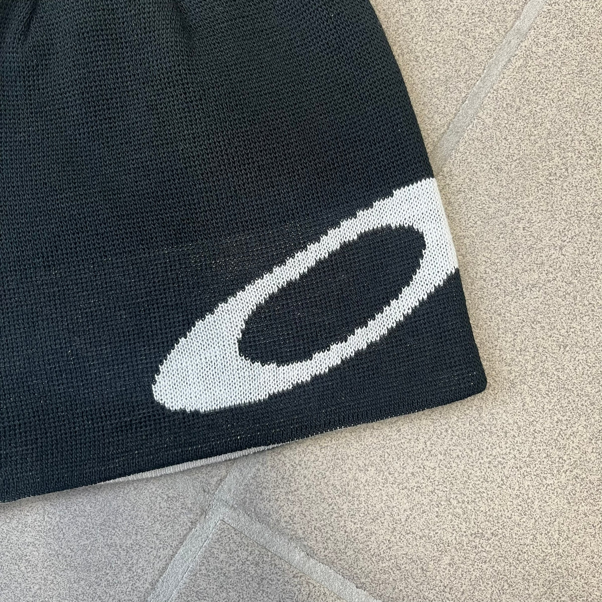 Oakley Ellipse Black Side Beanie is a classic-fit, fine-knit beanie made from 100% acrylic, with a reversible two-sided build. It has a contrasting white jacquard Oakley Ellipse logo on the side and a small logo flag. Designed for casual wear and outdoor performance with reliable warmth and fit.