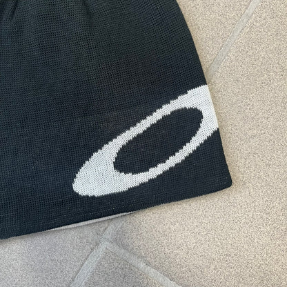 Oakley Ellipse Black Side Beanie is a classic-fit, fine-knit beanie made from 100% acrylic, with a reversible two-sided build. It has a contrasting white jacquard Oakley Ellipse logo on the side and a small logo flag. Designed for casual wear and outdoor performance with reliable warmth and fit.