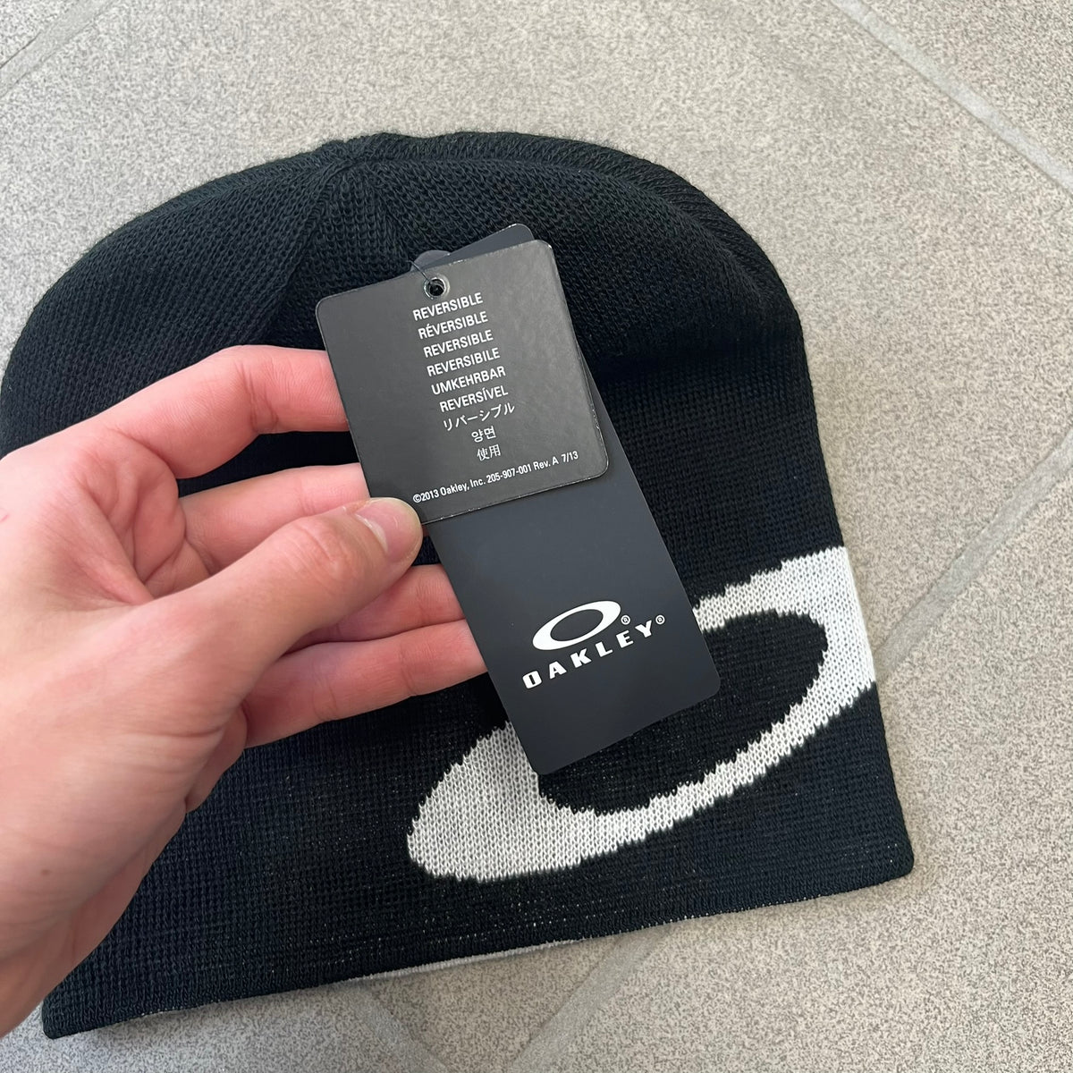 Oakley Ellipse Black Side Beanie is a classic-fit, fine-knit beanie made from 100% acrylic, with a reversible two-sided build. It has a contrasting white jacquard Oakley Ellipse logo on the side and a small logo flag. Designed for casual wear and outdoor performance with reliable warmth and fit.