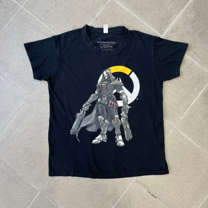 Overwatch 2017 Reaper Black Tee features a black construction with a full-color graphic of Reaper standing with his guns in front of the Overwatch logo, with a small “TM” mark beside it. Finished with a licensed 2017 Overwatch Gaya neck tag.
