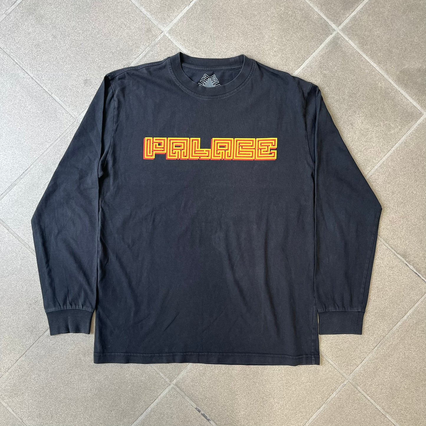 Palace FW18 Mazin Black Longsleeve features a black 100% cotton construction with a Palace logo printed on the chest. The logo is made from a maze-style graphic in yellow and red. Released on November 23, 2018.