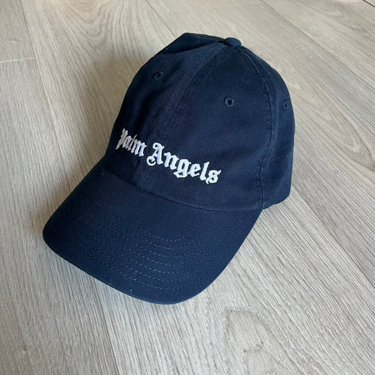 Palm Angels Classic Logo Navy Baseball Cap crafted from 100% cotton. Features white embroidered Palm Angels logos on the front and back in gothic-inspired lettering. A timeless streetwear accessory with a clean navy finish.