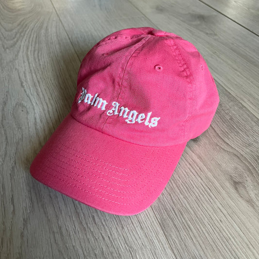 Palm Angels Classic Logo Pink Baseball Cap crafted from 100% cotton. Features white embroidered Palm Angels logos on the front and back in gothic-inspired lettering. A clean, minimal statement piece with a bold color pop.