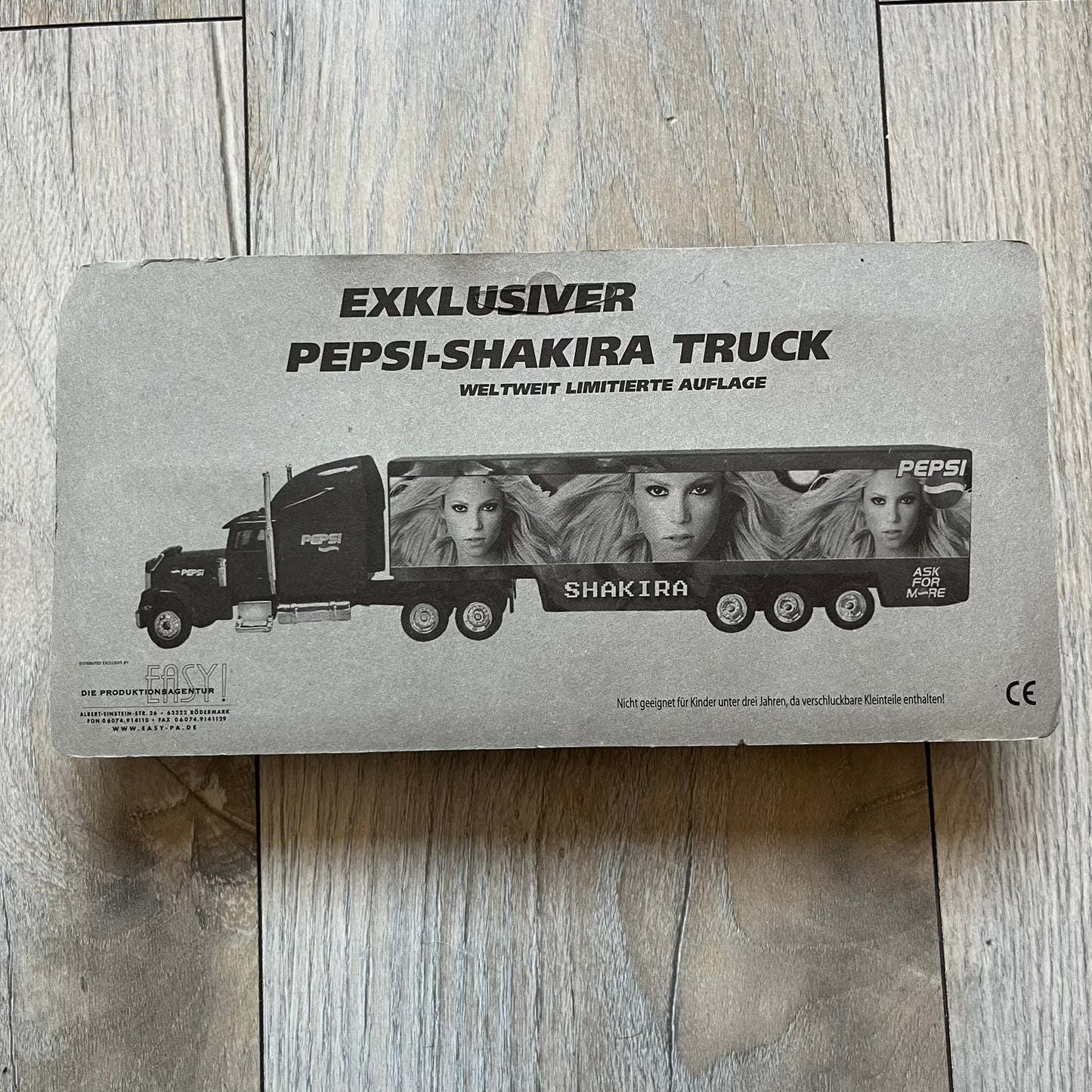 Pepsi 2000’s Shakira 1:87 Delivery Truck Model is a limited edition promotional model featuring a blue Pepsi delivery truck covered with graphics of Shakira alongside Pepsi logos and name text. The model remains in its original clear plastic display case attached to a printed cardboard backing with Pepsi and Shakira branding. This German edition promotional piece was produced as part of early 2000s Pepsi marketing campaigns.