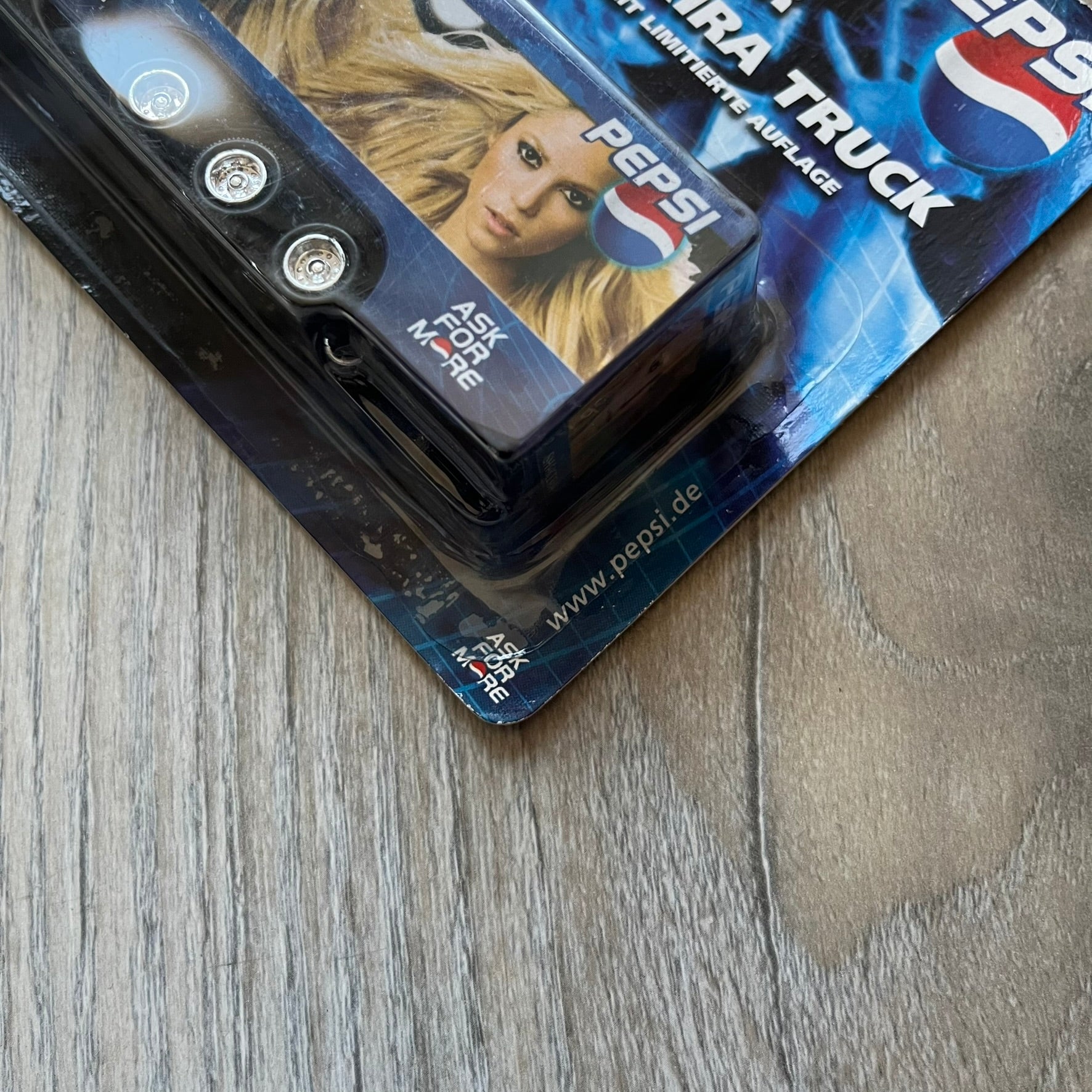 Pepsi 2000’s Shakira 1:87 Delivery Truck Model is a limited edition promotional model featuring a blue Pepsi delivery truck covered with graphics of Shakira alongside Pepsi logos and name text. The model remains in its original clear plastic display case attached to a printed cardboard backing with Pepsi and Shakira branding. This German edition promotional piece was produced as part of early 2000s Pepsi marketing campaigns.