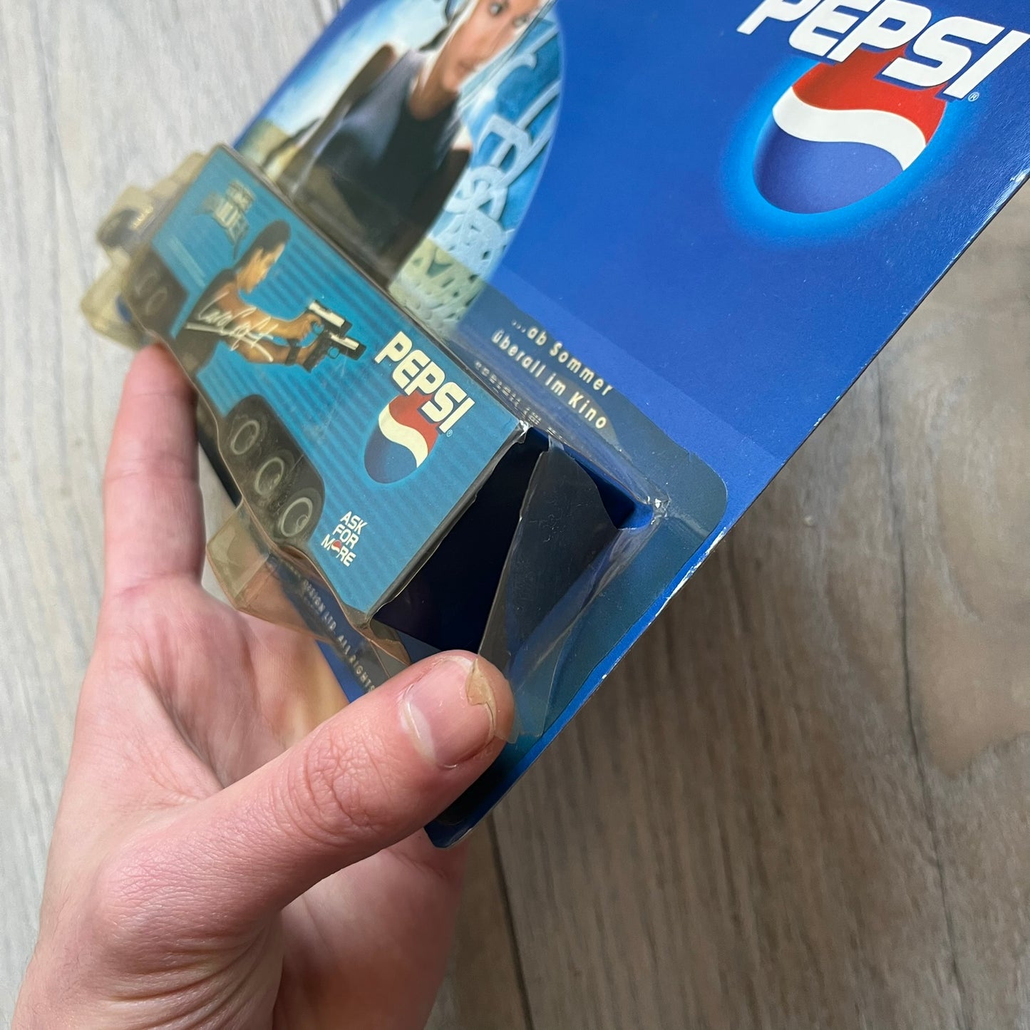 Pepsi 2001 Lara Croft Tomb Raider 1:87 Delivery Truck Model is a promotional die-cast style truck released alongside the film Lara Croft: Tomb Raider. The model features a blue Pepsi delivery truck with a large graphic of Lara Croft and Pepsi branding on the sides. It comes displayed in a clear plastic case attached to a printed cardboard backing with Tomb Raider and Pepsi graphics. The bottom of the case includes 2001 Paramount Pictures licensing.