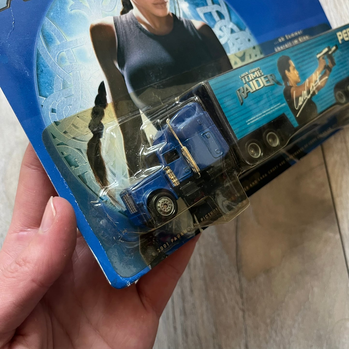 Pepsi 2001 Lara Croft Tomb Raider 1:87 Delivery Truck Model is a promotional die-cast style truck released alongside the film Lara Croft: Tomb Raider. The model features a blue Pepsi delivery truck with a large graphic of Lara Croft and Pepsi branding on the sides. It comes displayed in a clear plastic case attached to a printed cardboard backing with Tomb Raider and Pepsi graphics. The bottom of the case includes 2001 Paramount Pictures licensing.