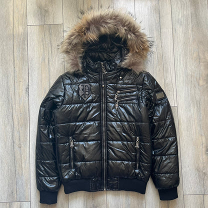 Philipp Plein 2010's Black Waxed Puffer Jacket is a black puffer jacket with a removable fur-trimmed hood attached by zipper. The jacket features heavy silver-tone hardware throughout, including large zipper pulls shaped as crosses with a skull in the center. The right chest has a crystal “P” patch set, while the left chest features two zip pockets. The hood drawstrings are finished with silver skull tips marked with a “P.”

One shoulder is finished with metal Philipp Plein logo plaque. The interior lining 