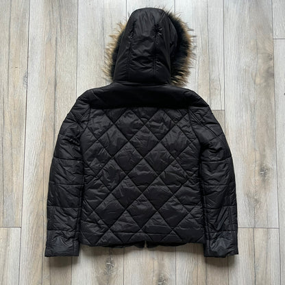 Philipp Plein 2010's Fur Hood Puffer Jacket is a black puffer jacket with a removable fur-trimmed hood attached by zipper. The jacket features heavy silver-tone hardware throughout, including 3 large zipper pulls used on the front pockets, main zipper and one drawstring ending. The right arm has a black “P” patch set with crystals.