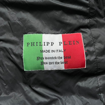 Philipp Plein 2010's Fur Hood Puffer Jacket is a black puffer jacket with a removable fur-trimmed hood attached by zipper. The jacket features heavy silver-tone hardware throughout, including 3 large zipper pulls used on the front pockets, main zipper and one drawstring ending. The right arm has a black “P” patch set with crystals.