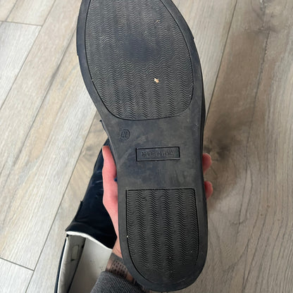 Philipp Plein Navy Skull Slip-Ons are dark navy slip-on sneakers with white interior lining. The front features large raised skull logos, while the sole side displays the Philipp Plein text/logo. Made in Italy, the interior includes an authentic PP tag.