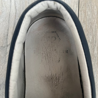 Philipp Plein Navy Skull Slip-Ons are dark navy slip-on sneakers with white interior lining. The front features large raised skull logos, while the sole side displays the Philipp Plein text/logo. Made in Italy, the interior includes an authentic PP tag.