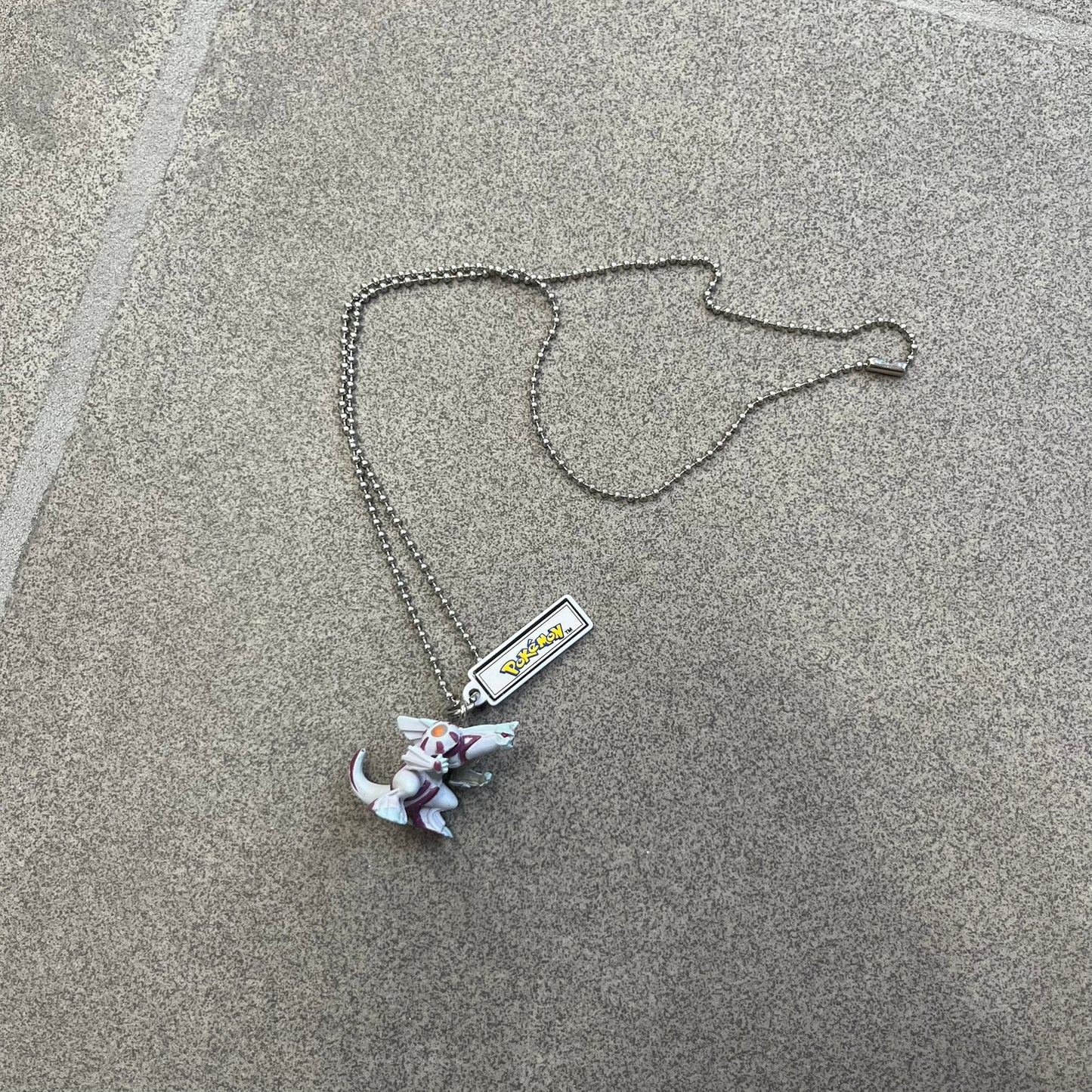 Pokémon 2008 Palkia Necklace is a converted Palkia key chain turned into a wearable pendant. It features a small 3D Palkia figure from the Pokémon franchise with an attached Pokémon tag containing licensing details on the back. The pendant design comes from a 2008 key chain release.