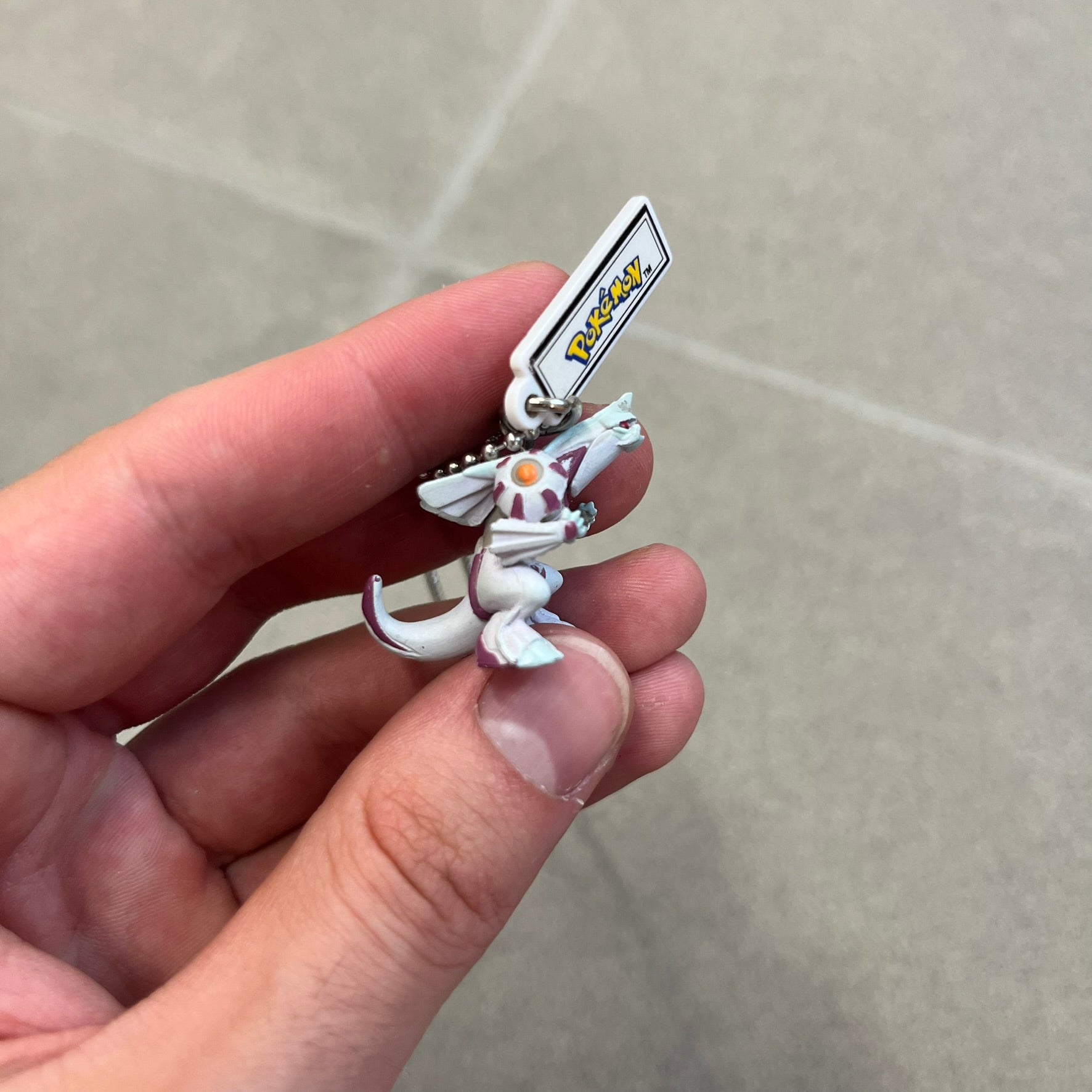 Pokémon 2008 Palkia Necklace is a converted Palkia key chain turned into a wearable pendant. It features a small 3D Palkia figure from the Pokémon franchise with an attached Pokémon tag containing licensing details on the back. The pendant design comes from a 2008 key chain release.