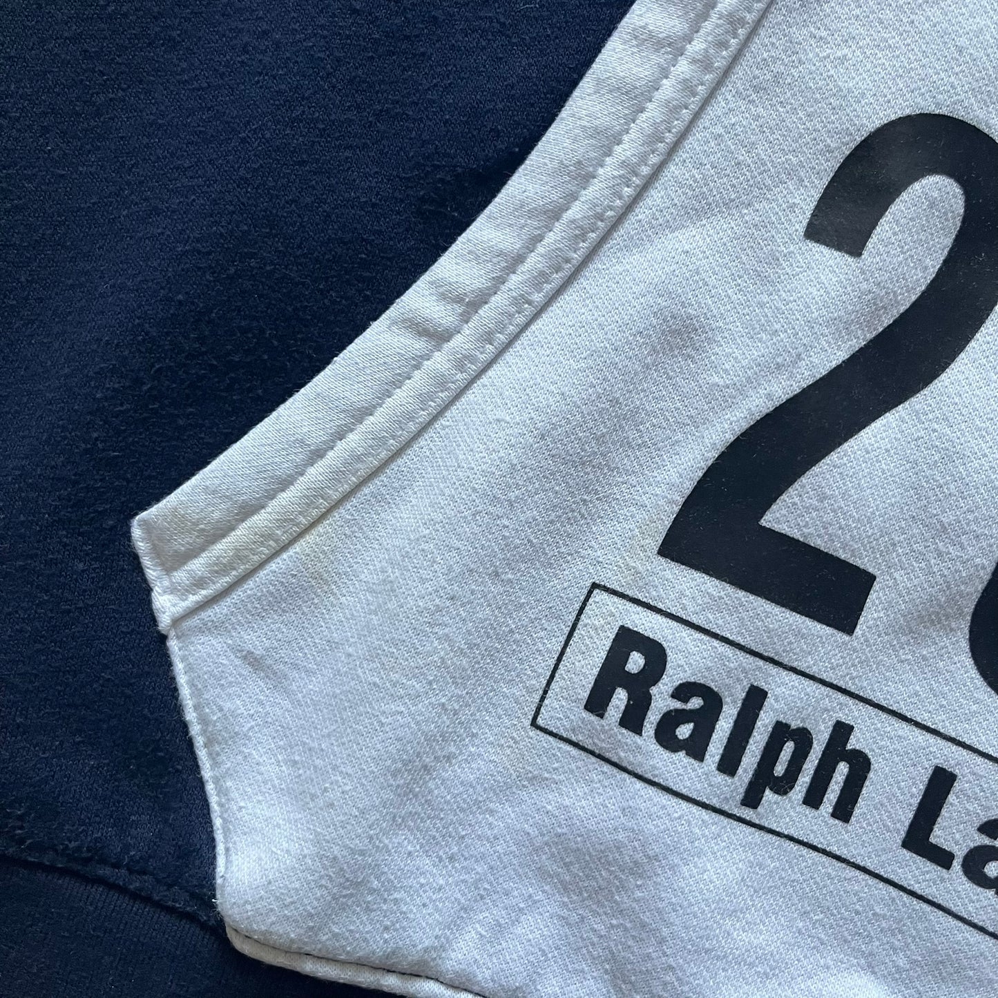 Polo Ralph Lauren x Fortnite 2022 Hoodie featuring a two-tone split design in blue and navy with a white hood. The front showcases a large white panel with “2022” text, Ralph Lauren Est. 1967 branding, and a Fortnite logo, along with an oversized embroidered Polo logo above. A limited collaboration piece combining Ralph Lauren’s heritage aesthetic with Fortnite’s playful edge.