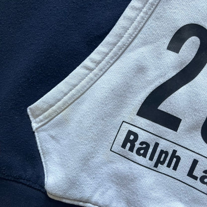 Polo Ralph Lauren x Fortnite 2022 Hoodie featuring a two-tone split design in blue and navy with a white hood. The front showcases a large white panel with “2022” text, Ralph Lauren Est. 1967 branding, and a Fortnite logo, along with an oversized embroidered Polo logo above. A limited collaboration piece combining Ralph Lauren’s heritage aesthetic with Fortnite’s playful edge.