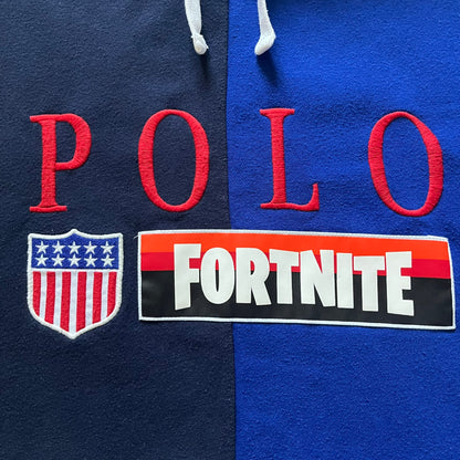 Polo Ralph Lauren x Fortnite 2022 Hoodie featuring a two-tone split design in blue and navy with a white hood. The front showcases a large white panel with “2022” text, Ralph Lauren Est. 1967 branding, and a Fortnite logo, along with an oversized embroidered Polo logo above. A limited collaboration piece combining Ralph Lauren’s heritage aesthetic with Fortnite’s playful edge.