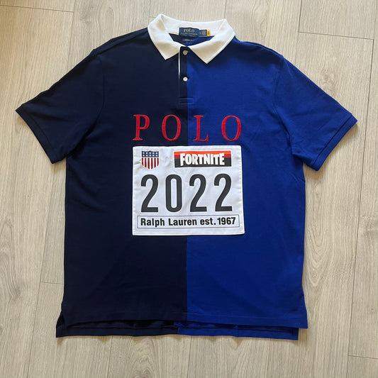 Polo Ralph Lauren x Fortnite 2022 Polo Shirt featuring a two-tone split design in blue and navy with a crisp white collar. The front showcases a large white panel with “2022” text, Ralph Lauren Est. 1967 branding, and a Fortnite logo, along with an oversized embroidered Polo logo above. A limited collaboration piece combining Ralph Lauren’s heritage aesthetic with Fortnite’s playful edge.