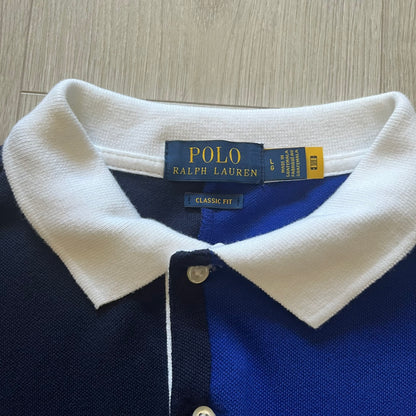 Polo Ralph Lauren x Fortnite 2022 Polo Shirt featuring a two-tone split design in blue and navy with a crisp white collar. The front showcases a large white panel with “2022” text, Ralph Lauren Est. 1967 branding, and a Fortnite logo, along with an oversized embroidered Polo logo above. A limited collaboration piece combining Ralph Lauren’s heritage aesthetic with Fortnite’s playful edge.