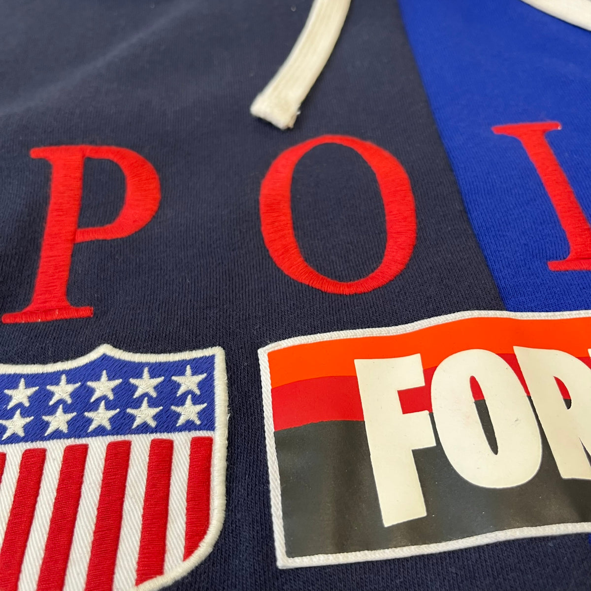 Polo Ralph Lauren x Fortnite 2022 Hoodie featuring a two-tone split design in blue and navy with a white hood. The front showcases a large white panel with “2022” text, Ralph Lauren Est. 1967 branding, and a Fortnite logo, along with an oversized embroidered Polo logo above. A limited collaboration piece with paper tags.