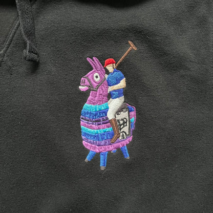 Polo Ralph Lauren x Fortnite black hoodie featuring a detailed embroidered purple Fortnite llama with the RL rider logo placed on top. Made from a 66% cotton and 34% polyester blend, it has a classic pullover construction with an attached hood and front kangaroo pocket. The embroidery is positioned on the left chest and stands out with clean stitching and sharp detail.