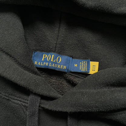 Polo Ralph Lauren x Fortnite black hoodie featuring a detailed embroidered purple Fortnite llama with the RL rider logo placed on top. Made from a 66% cotton and 34% polyester blend, it has a classic pullover construction with an attached hood and front kangaroo pocket. The embroidery is positioned on the left chest and stands out with clean stitching and sharp detail.