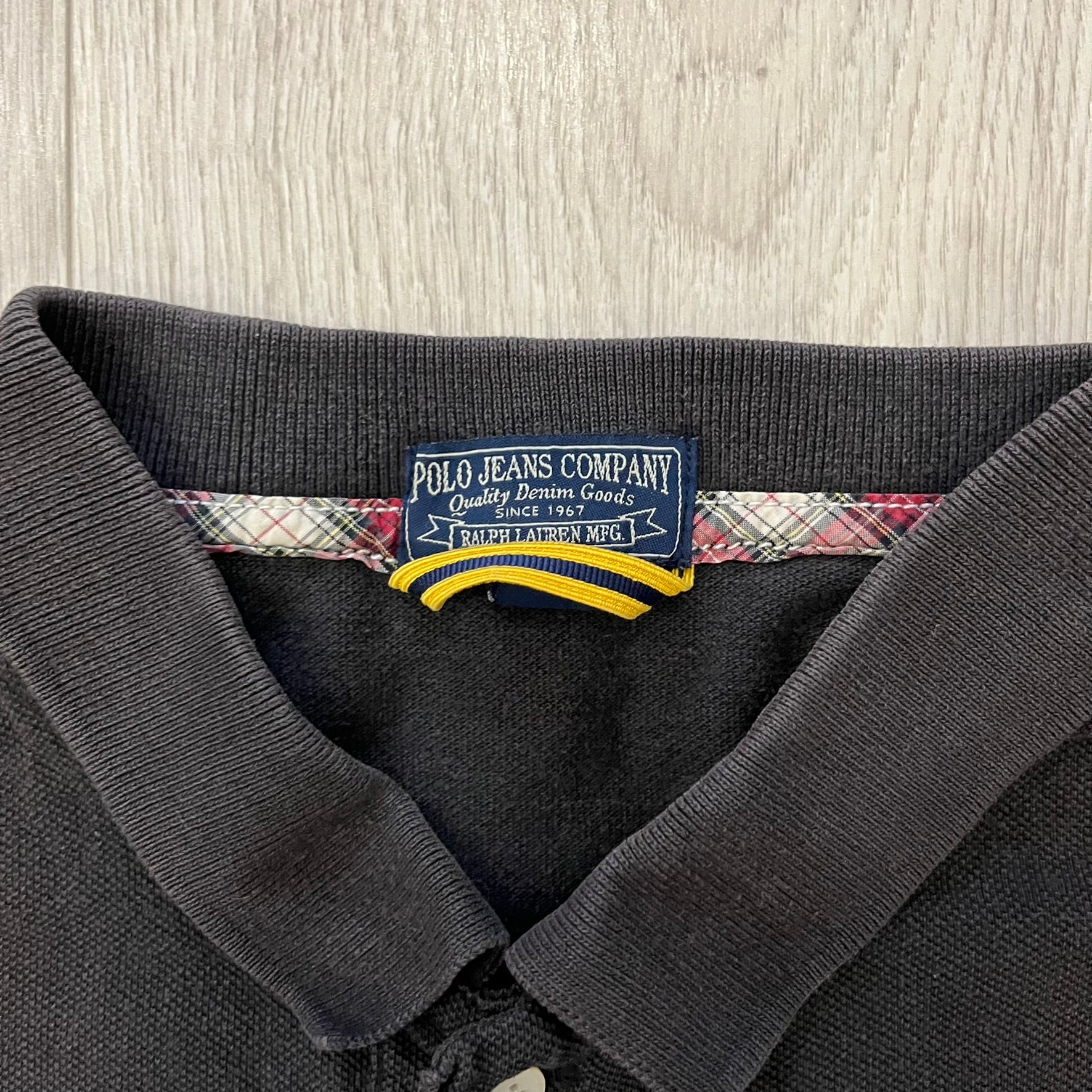 Polo Ralph Lauren ’67 Crest Polo in dark brown. Features an embroidered crest on the left chest with “1967” detail and a big red “67” patch on the sleeve. Classic cotton polo construction with short sleeves and ribbed collar.