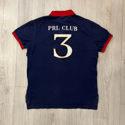 Ralph Lauren’s “PRL Club” Big Pony Polo stands out with detailed front embroidery, combining a Big Pony motif, Challenge Cup text, and a large crest. The navy body is paired with red accents on the collar and sleeves, with a signature oversized “3” and PRL Club branding on the back.