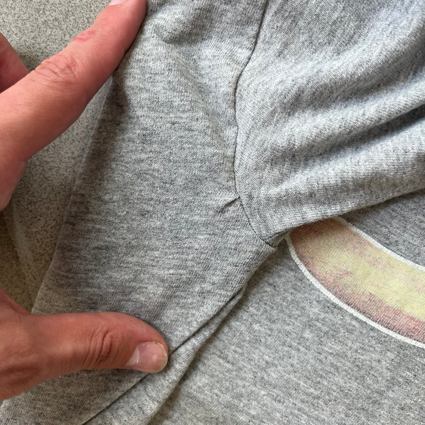 Porn Star Clothing 90's Fruits Gray Tee features a grey T-shirt with an apple, banana, and pear graphic on the chest, arranged as a you know what. A small Porn Star logo is printed underneath, with the “Good Clothing for Bad People” branding on the neck tag. The shirt has two professionally repaired holes under the armpits.