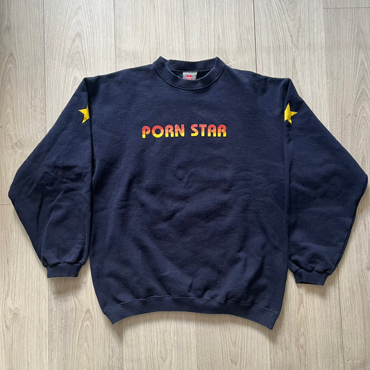 Navy blue sweatshirt with 'Porn Star' text and stars on a wooden surface