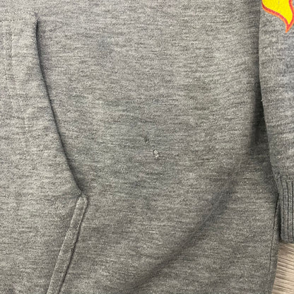 Porn Star Clothing Thrasher Hoodie from the 1990s, made in a gray cotton fabric. The front features a large flame-style “Pornstar” logo that is a spin-off of the Trasher one, with matching flame graphics running down both sleeves. Designed with an adjustable drawstring hood, front kangaroo pocket, and ribbed cuffs and hem. Finished with the original “Must Be 18 Or Over” Porn Star Clothing tag.