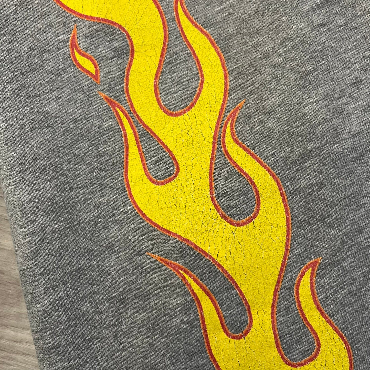Porn Star Clothing Thrasher Hoodie from the 1990s, made in a gray cotton fabric. The front features a large flame-style “Pornstar” logo that is a spin-off of the Trasher one, with matching flame graphics running down both sleeves. Designed with an adjustable drawstring hood, front kangaroo pocket, and ribbed cuffs and hem. Finished with the original “Must Be 18 Or Over” Porn Star Clothing tag.