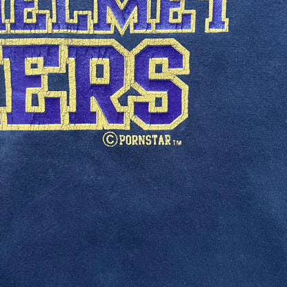 Black T-shirt with a purple football helmet graphic featuring a “P” letter. “Porn Star” text above the helmet in purple with a yellow outline, and “Helmet Packers” text below in purple with a yellow outline. Includes a small Porn Star copyright logo. Vintage piece.