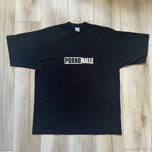PornoRalle TV 1990s Black Tee is a black short-sleeve T-shirt made on a Jerzees blank. The front features a white PornoRalle logo on the chest with small “TV Total” text beneath. This minimalist design dates from the 1990s.