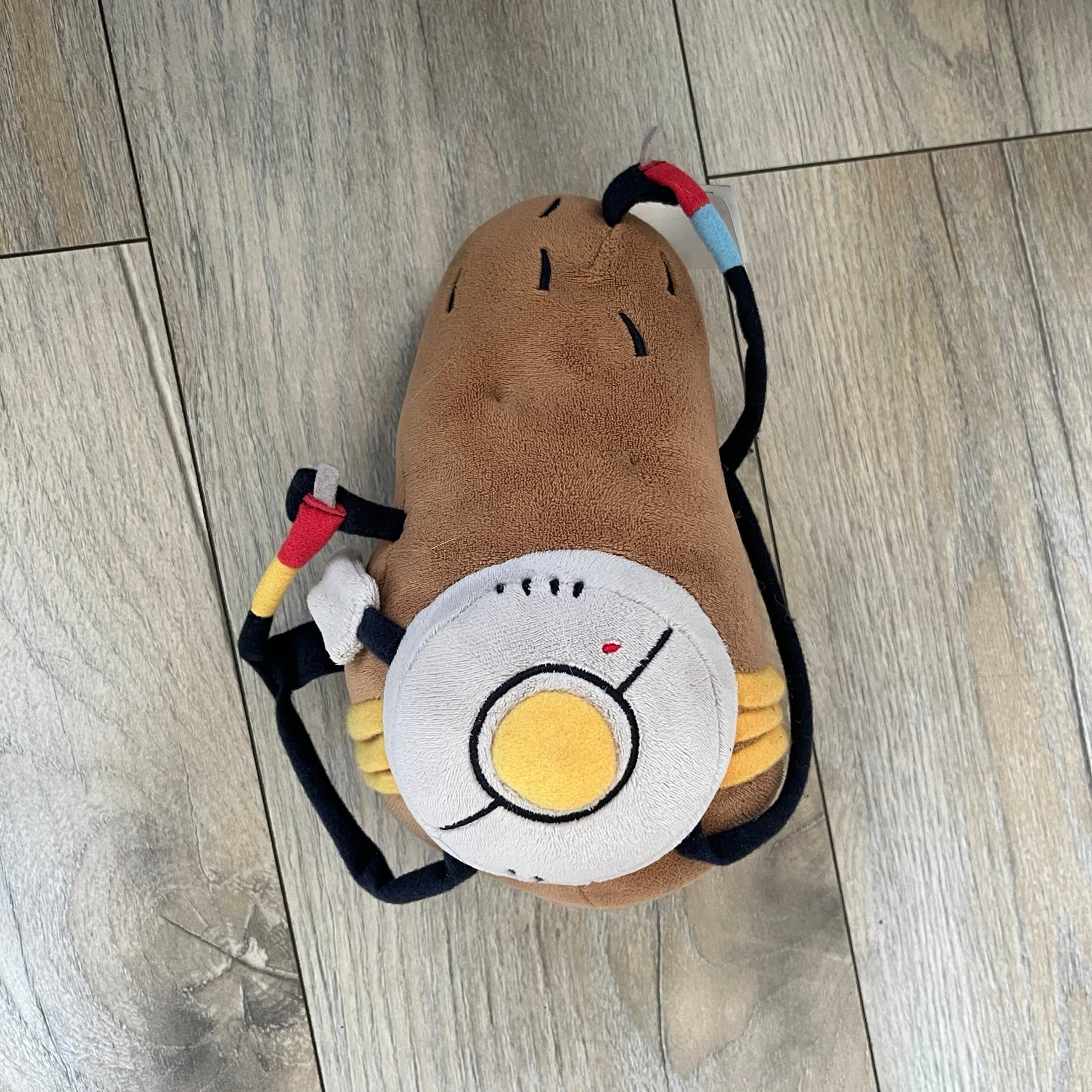 Portal 2 GLaDOS PotatOS 2013 ThinkGeek Talking Plush is a collectible plush toy based on the PotatOS version of GLaDOS from the Portal 2 video game. The plush features a soft construction with integrated electronics, including 10 pre-recorded voice lines activated by a button, along with a light-up eye effect. It requires 3 AA batteries (not included), includes an on/off switch hidden in the back compartment, and was produced by ThinkGeek in 2013.