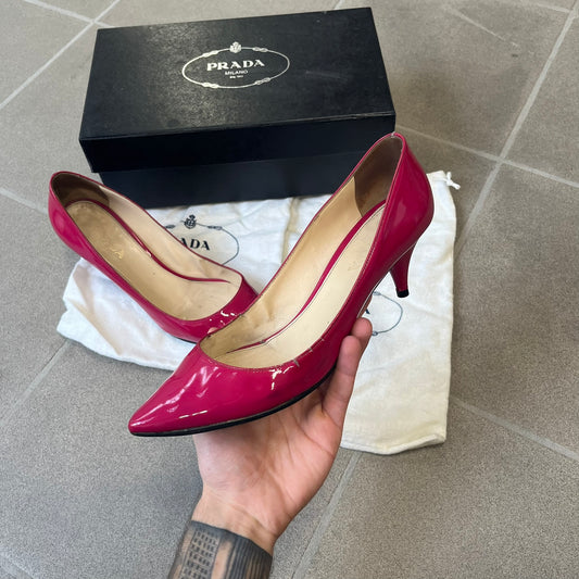 Prada 2000's Patent Leather Magenta Kitten Heels are made in Italy from magenta patent leather with a beige interior and sole, featuring a gold-tone metal Prada logo on the bottom and Prada branding on the insole. They come with the original box and two dust bags; the bottom and heel tip have been professionally repaired.